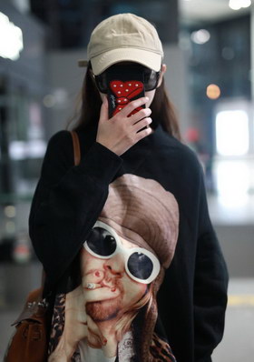 组图:唐嫣现身上海机场 举手机遮脸低首浅笑